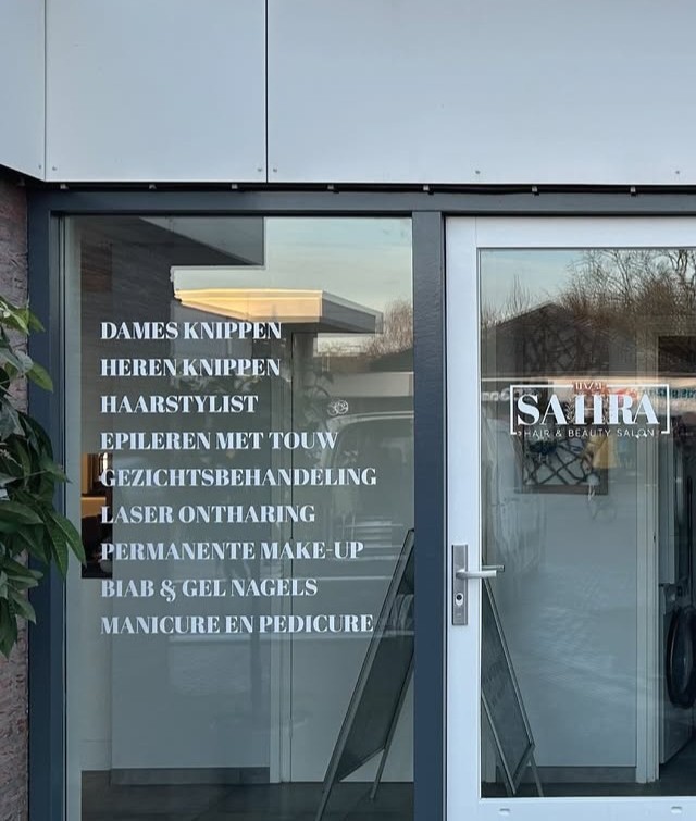 De deur en het raam van de salon met de behandelingen op het glas